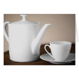 Close-up of a cup and a saucer with a tea kettle
