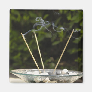Close-up of burning incense sticks with pebbles magnet