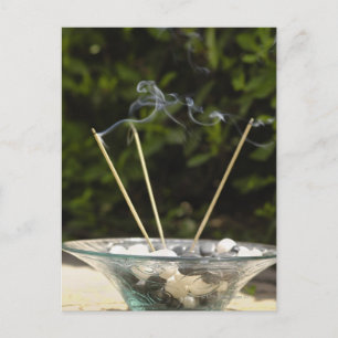 Close-up of burning incense sticks with pebbles postcard