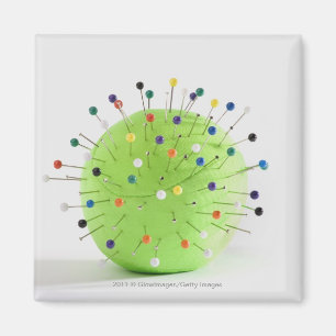 Close-up of straight pins inserted into a ball magnet