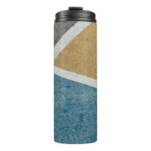 Closeup grey, yellow, and blue painted pavement thermal tumbler