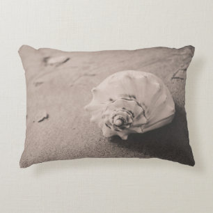 Closeup photo of white seashell on sand accent pillow