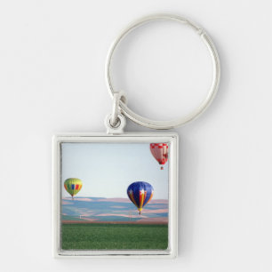 Colourful hot air balloons float over wheat keychain