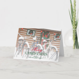 Couple of snow covered bikes near wreathed lodge holiday card