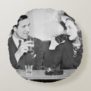 Couple sitting together in a restaurant flirting w round pillow