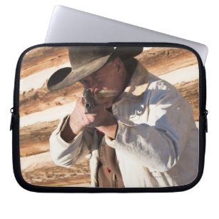 Cowboy aiming his gun, standing by an old log laptop sleeve