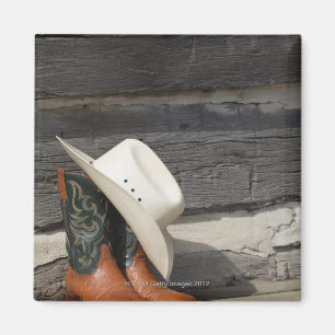 Cowboy hat on cowboy boots outside a log cabin magnet