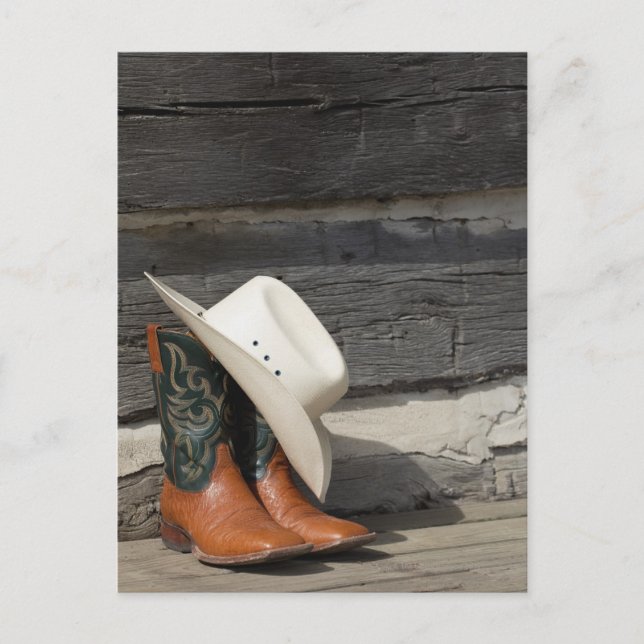 Cowboy hat on cowboy boots outside a log cabin postcard (Front)