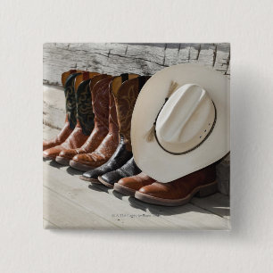 Cowboy hat on row of cowboy boots outside a log 2 inch square button