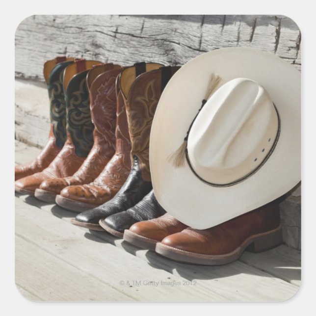 Cowboy hat on row of cowboy boots outside a log square sticker (Front)