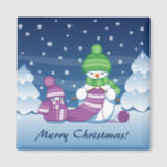 Crafty Snowman Knitting Scarf Magnet<br><div class="desc">Vector illustration of two adorable cartoon snowmen dressed in knitted hats and scarves. The big crafty snowman is knitting an oversized scarf for the little one. The scarf is already wrapped several times around the cute little snowman.</div>