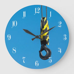 Crane hook with yellow and black stripes hanging large clock