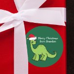 Cute Christmas Dinosaur in Santa Hat Custom Kids Classic Round Sticker<br><div class="desc">Awesome green dinosaur smiling and looking very cute in a holiday red Santa hat. Kids will love this cool green holiday party favour label. Customize these Christmas gift sticker with your own text in white.</div>