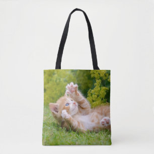 Cute funny cat kitten playing in a flowery garden tote bag