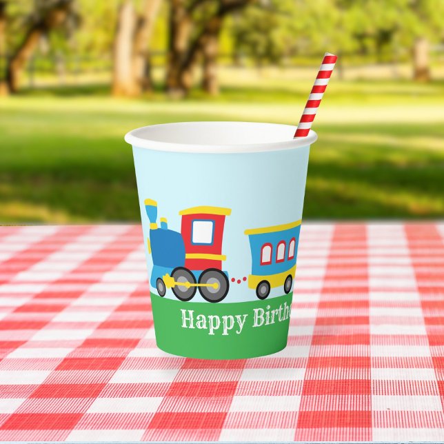 Cute Train Birthday Party Paper Cups (A paper cup decorated with a cute cartoon train sits on a picnic table in a park.)