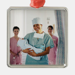 Delivery room nurse holding baby, nurses in metal ornament