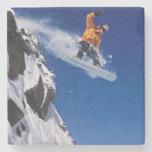 Dessous-de-verre En Pierre Homme sur un snowboard sautant d'une corniche à