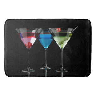 Different cocktails in martini glasses on black bath mat