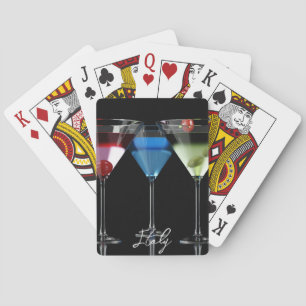 Different cocktails in martini glasses on black playing cards