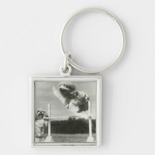 Dogs jumping over miniature high jump bar keychain