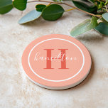 Elegant Coral Orange Round Monogram Script Coaster<br><div class="desc">An elegant sandstone coaster featuring a red orange serif initial and custom family name in script, framed by a white circle on a soft coral peach pink background. The warm, sunset-inspired palette adds a lively pop of colour to any home. A cheerful personalized gift for housewarmings, summer entertaining, or anyone...</div>