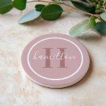 Elegant Dusty Rose Round Monogram Script Coaster<br><div class="desc">An elegant sandstone coaster featuring a dusty rose serif initial and custom family name in script, framed by a white circle on a soft light mauve background. The muted, romantic tones create a sophisticated feminine accent that pairs beautifully with neutral or blush decor. A lovely personalized gift for housewarmings, bridal...</div>