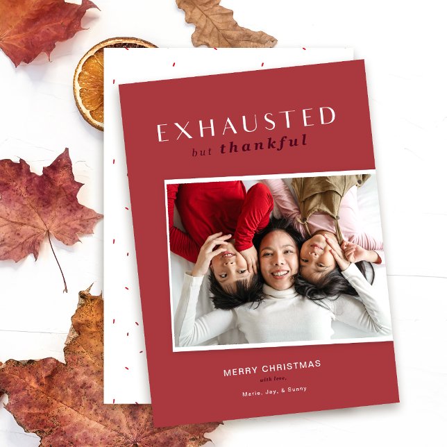 Exhausted but Thankful Funny Christmas Card (Red exhausted but thankful photo holiday card mock up shown on white table with fall leaves.)