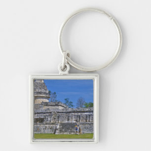 Family of tourists walk past ancient Mayan Keychain