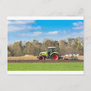 Farmer on tractor plowing sandy soil in spring postcard