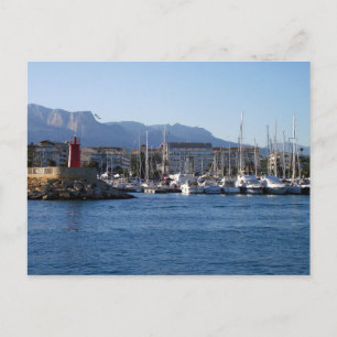 Faro rojo y veleros en el puerto postcard