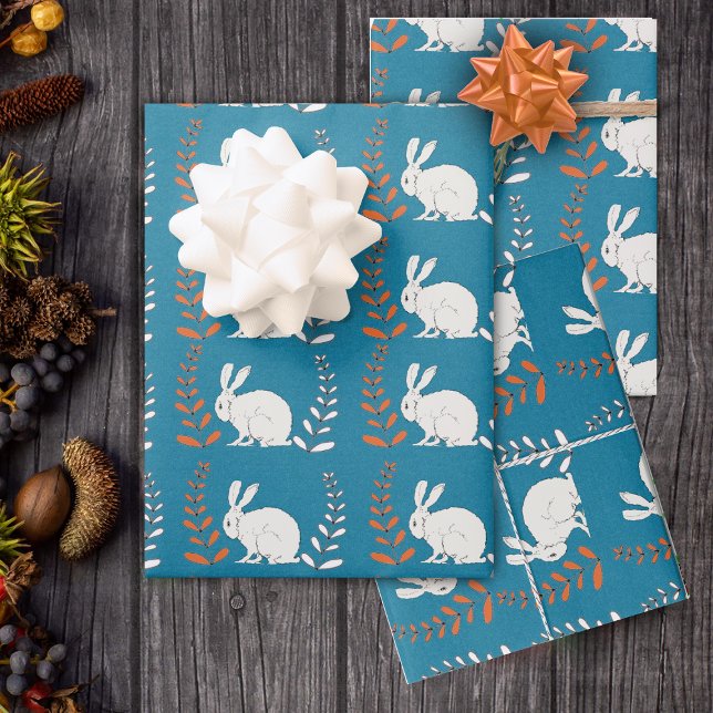 Feuille De Papier Cadeau assise élégante Fleurs de lapin blanc foncé bleu (Rows of white rabbits with orange and white flower plants on roll of dark blue wrapping paper.)