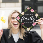 Finally | Custom School and Class Year Graduation Cap Topper<br><div class="desc">Cute personalized grad cap topper features your school and class year with "finally!" in the centre,  in white brush script lettering on a black background adorned with pink watercolor flowers and green foliage.</div>