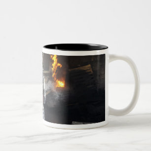 Firefighters extinguish a fire in a training ro Two-Tone coffee mug