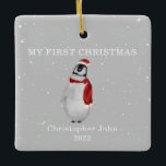 First Christmas Baby Penguin Grey Snow Ceramic Ornament<br><div class="desc">Illustration of a baby penguin wearing a santa hat and matching scarf surrounded by snowflakes with a grey background.  Text says,  "My first Christmas."  Personalize the name and year.</div>