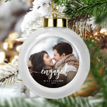 First Christmas Engaged Custom Photo White Script Ceramic Ball Christmas Ornament<br><div class="desc">Commemorate your engagement with this beautiful modern keepsake ornament. The white text reads "Our first Christmas engaged, " with the word "engaged" in elegant calligraphy script with decorative swashes before and after. Replace the sample image with your favourite photo, and add your names and the year. A black gradient filter...</div>