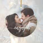 First Christmas Engaged Custom Photo White Script Ceramic Ornament<br><div class="desc">Commemorate your engagement with this beautiful modern keepsake ornament. The white text reads "Our first Christmas engaged, " with the word "engaged" in elegant calligraphy script with decorative swashes before and after. Replace the sample image with your favourite photo, and add your names and the year. A black gradient filter...</div>