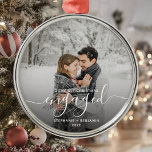 First Christmas Engaged Custom Photo White Script Metal Ornament<br><div class="desc">Commemorate your engagement with this beautiful modern keepsake ornament. The white text reads "Our first Christmas engaged, " with the word "engaged" in elegant handwriting script with flourishes before and after. Replace the sample image with your favourite photo, and add your names and the year. A black gradient filter helps...</div>