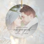 First Christmas Engaged Photo Grey Modern Script Ceramic Ornament<br><div class="desc">Commemorate your engagement with this beautiful modern keepsake ornament. The charcoal grey text reads "Our first Christmas engaged, " with the word "engaged" in elegant calligraphy script with decorative swashes before and after. Replace the sample image with your favourite photo, and add your names and the year. A white gradient...</div>