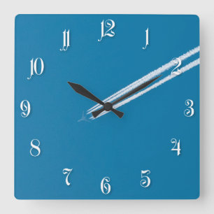 Flying airplane on a blue sky background square wall clock