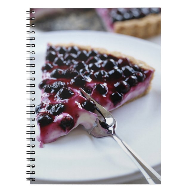 Fork slicing blueberry pie on plate notebook (Front)