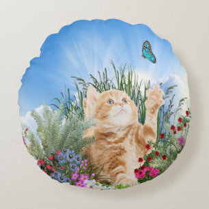 Ginger kitten playing with a butterfly round pillow