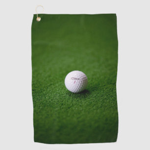 Golf ball on a green surface Golf Towels