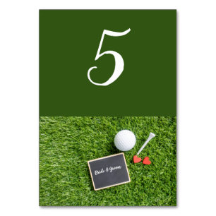 Golf ball with name on chalkboard are on green table number