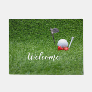 Golf ball with two red hearts are on green grass doormat