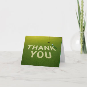 Golf ball with word thank you on putting green card