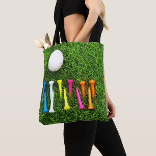Golf tees are on green grass. tote bag