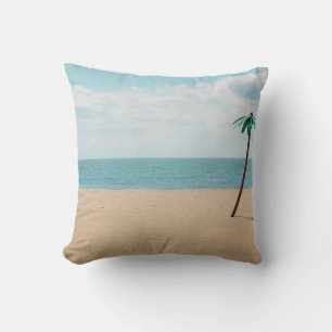 Green artificial palm tree on seashore throw pillow