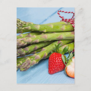 Green asparagus with strawberries on wooden postcard