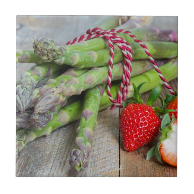 Green asparagus with strawberries on wooden tile (Front)