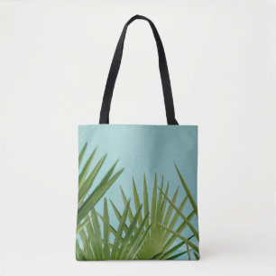 Green palm plant near body of water tote bag